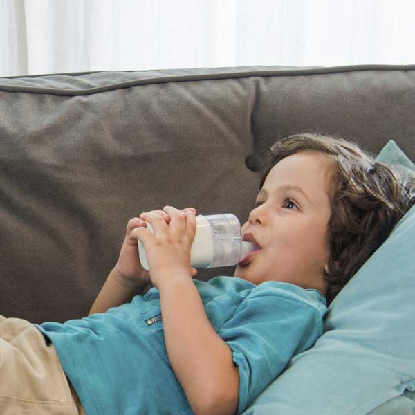 Omron MicroAir U100 Nebuliser young boy using nebuliser laying on sofa